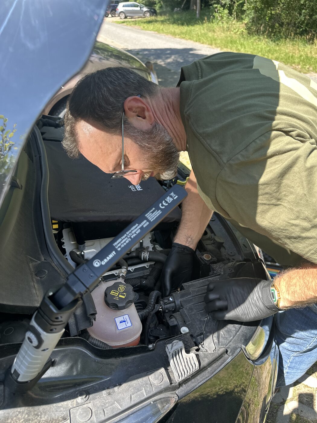 Eugen Hinkel bei der technischen Prüfung unter der Motorhaube eines e Autos